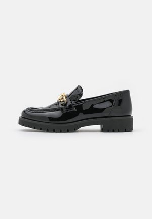 Mocassin en cuir verni noir avec semelle épaisse et chaîne décorative dorée sur le dessus, montré de profil sur fond blanc.