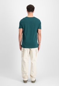 Kortærmet t-shirt med rund hals i mørk teal, parret med krèmefarvede cargo bukser med sidelommer og en afslappet pasform.