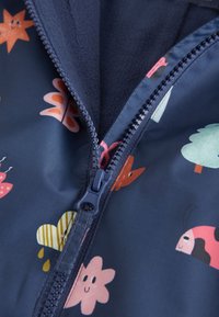 Giacca blu navy con motivo floreale e animale colorato, dotata di cerniera completa e fodera in pile al colletto per un maggiore comfort.