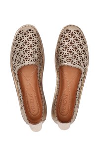 Beige slip-on shoes with laser-cut floral patterns, soft leather upper, brown leather lining, and a textured sole. Rounded toe design.