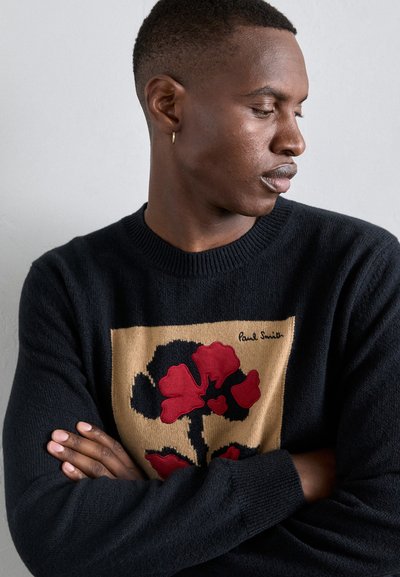 Μαύρο πουλόβερ με floral σχέδιο σε κόκκινο και μαύρο σε μπεζ φόντο; ριμπ κολάρο �και μανσέτες; υπογραφή "Paul Smith" στο σχέδιο.