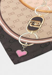 La bufanda de seda presenta un fondo beige con un patrón de cadenas, herrajes dorados y un charm en forma de corazón rosa adjunto.