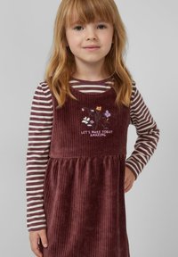 Bordeauxfarbendes Cordkleid mit bestickten Blumen und Text. Übereinander getragen mit einem gestrickten Langarmshirt in Creme und Bordeauxstreifen. Weicher Stoff.