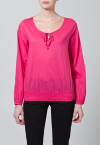 Rosa långärmad topp med rundad halsringning, med en knytning framtill och en smockad midja. Slen textur.