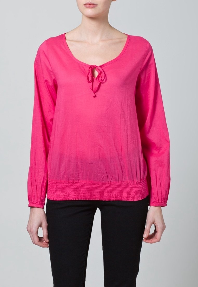 Rosa långärmad topp med rundad halsringning, med en knytning framtill och en smockad midja. Slen textur.