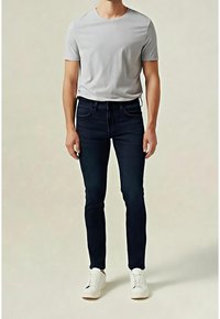 Camiseta gris de cuello redondo, vaqueros ajustados azul oscuro y zapatillas blancas. Tejido suave con un ajuste casual y detalles mínimos de costuras.