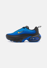 Men’s athletic shoe with black and blue upper, yellow Nike swoosh, thick black and blue sole, and visible air cushioning at heel.
