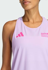 Svijetloplavi atletski top s prozračnim, teksturiranim materijalom. Sadrži ružičasti Adidas logo i tekst "BMW BERLIN MARATHON" na prednjoj strani.