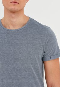 T-shirt grigio a maniche corte con scollatura rotonda, realizzato in tessuto testurizzato. Maniche con risvolto e dettagli di cucitura discreti all'orlo delle maniche.