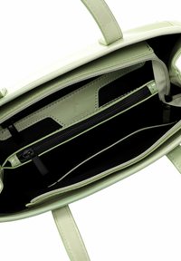 Interno di una borsa in pelle verde, con uno spazio aperto foderato di nero, un compartimento con cerniera e due tasche a soffietto.