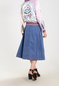 Jasnoróżowa i niebieska satynowa kurtka bombka z kwiatowym haftem, w połączeniu z niebieską spódnicą dżinsową i czarnymi sandałami na słupku.