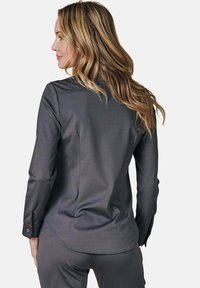 Dark gray long-sleeve shirt with a smooth texture and a curved hem. Buttoned cuffs and a plain design with no visible patterns or embellishments.