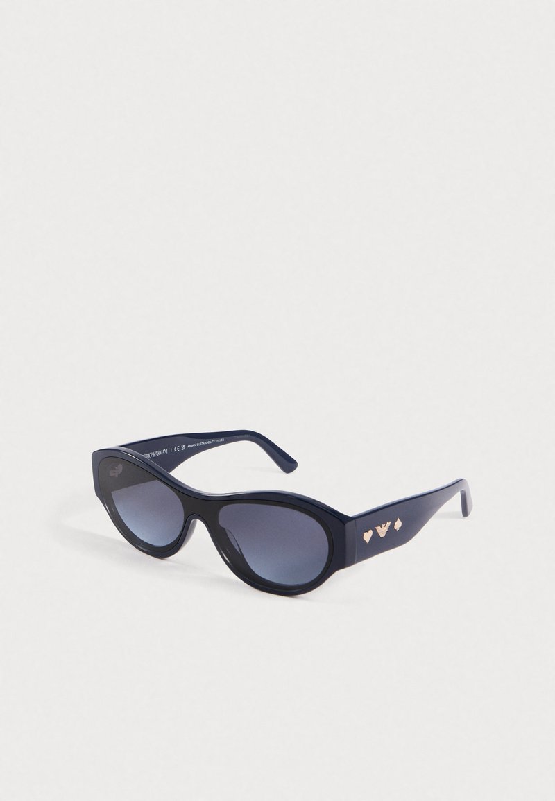Sunglasses u mornarsko plavoj boji s prekomjernim mačkastim oblikom. Imaju stakla s gradijentnim tonovima, sjajnu završnu obradu i ružičasto zlatne srčane akcentne detalje na sljepoočnicama.