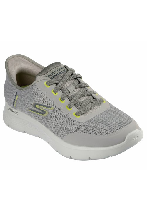 Chaussure de sport grise avec une tige en mesh texturé, des accents jaunes et une semelle blanche rembourrée. Elle dispose de lacets traditionnels et d'un détail de logo.