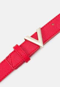 Ceinture en cuir texturé rouge avec une boucle en forme de V en ton doré et une sangle ajustable avec un passant.