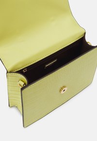 Krokodilpräglad handväska i livlig limegrön med guldfärgad hårdvara, med en slät satininteriör och en strukturerad rektangulär form.