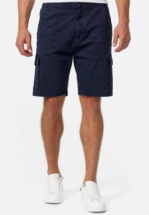 Shorts cargo bleu marine en mélange de coton, dotés de poches latérales, d'une coupe décontractée et d'une texture lisse. Portés avec des baskets blanches.