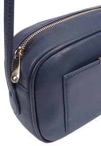 Blauwe leren schoudertas met een gouden rits en zilveren hardware. Heeft een voorvak met stiksels. Compacte, rechthoekige vorm.