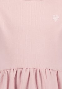 Abito in cotone a coste rosa chiaro con gonna arricciata e un piccolo dettaglio di cuoricino ricamato bianco sul petto.