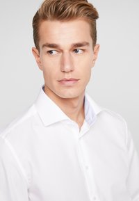 Witte dress shirt met een gestructureerde kraag, met subtiele gestreepte accenten op de binnenkraag. Glad stof, slim fit ontwerp.