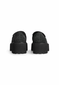Schwarze Slipper mit strukturiertem Muster, dickem Gummisohle und leicht erhöhtem Absatz, mit einer glatten Oberfläche und abgerundeter Ferse.