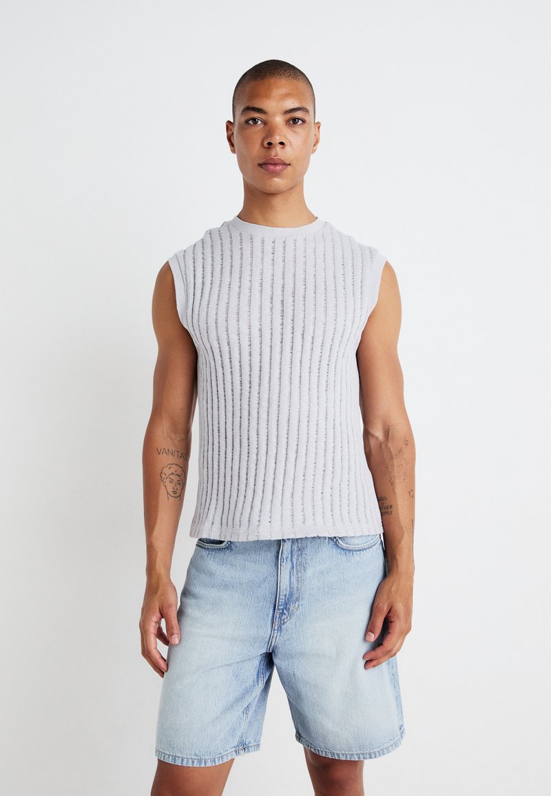 Gray sleeveless ribbed top, featuring vertical stripes, worn with light blue denim shorts. Smooth texture, crew neckline, fitted style.
