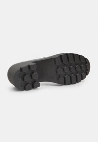Talpa de cizmă din cauciuc negru, cu o textură antiderapantă care prezintă modele hexagonale și rebrare pentru aderență. Margini netede și toc rotunjit.