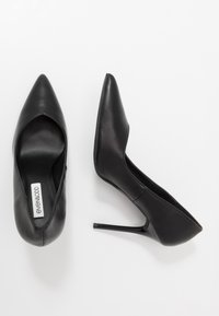 Schwarze High Heels aus glattem Leder, mit einer spitzen Zehenpartie und schlanker Silhouette, und einem dünnen Stiletto-Absatz.