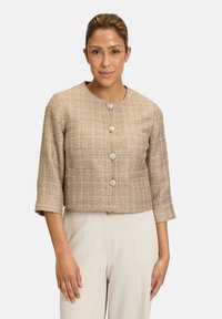Veste beige tissée courte avec un col rond, des manches longues, cinq fermetures à boutons argentés et deux poches avant. Texture lisse.
