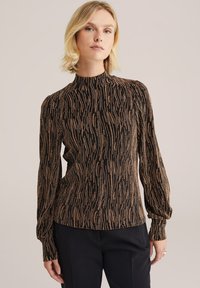 Maglia nera a maniche lunghe, collo alto, con un motivo testurizzato di strisce dorate e bronzee scintillanti, silhouette aderente e dettagli di maniche arricciate.