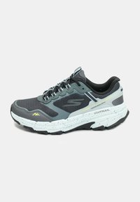 Grijze trailrunning schoenen met een bovenwerk van mesh, gestructureerde zwarte en grijze accenten, reflecterende details en een witte gespikkelde buitensool voor grip.