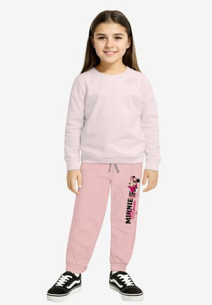 Felpa rosa e pantaloni della tuta rosa con grafica di Minnie Mouse, polsini elasticizzati e coulisse. Sneakers nere con suole bianche.