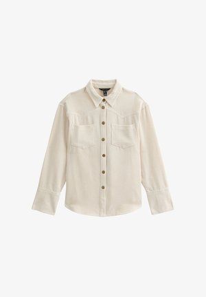 Camisa de pana beige claro con cierre de botones en la parte delantera, dos bolsillos en el pecho y un cuello clásico. Presenta un patrón texturizado y acanalado.
