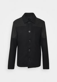 Svart jacka med knappar framtill, i ull med läderärmar, klassisk krage och sex runda knappar.