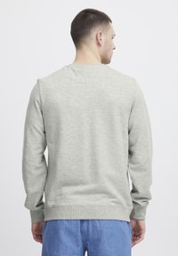 Lys grå genser med lange ermer og ribbestrikkede mansjetter. Myk tekstur, rund hals-design og en enkel, minimalistisk stil.