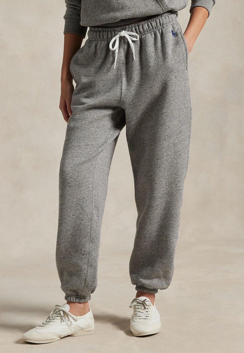 Grijze sweatpants van zachte stof, met een elastische tailleband en trekkoord, met omslagmanchetten en zijzakken. Gepaard met witte sneakers.