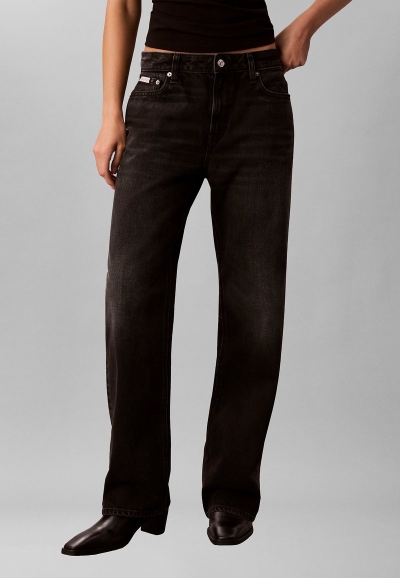 Jeans noirs à jambes droites en denim, dotés d'un design classique à cinq poches, de coutures visibles et d'une fermeture à bouton métallique.