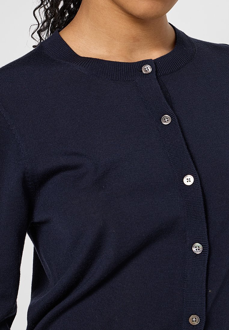 Navy-blaues Cardigan mit Rundhalsausschnitt, gerippter Textur und Knopfverschluss mit hellen Knöpfen an der Vorderseite.