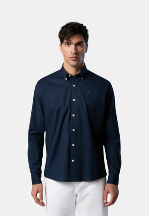 Camicia button-up blu navy con maniche lunghe, realizzata in materiale liscio. Presenta un piccolo logo e bottoni bianchi su un colletto strutturato.