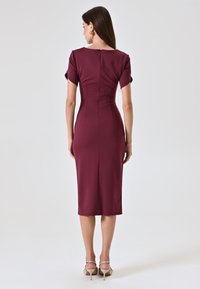 Bordeaux-farbenes knieumspielendes Kleid mit kurzen Ärmeln, taillierter Silhouette und Rückenreißverschluss; glatter Stoff mit subtiler Eleganz.