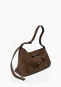 Braune Wildleder-Handtasche mit lockerem Design, ausgestattet mit einem langen Riemen und silbernen Ösendetails entlang der Kanten. Insgesamt glatte Textur.