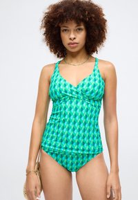 Tankini de color verde con un diseño geométrico en diferentes tonos de verde y azul. Tejido suave con tirantes ajustables y un corte ceñido.