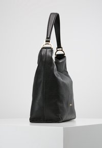 Musta nahkainen olkalaukku, jossa on teksturoitu pinta, yksi kahva ja kullansävyiset yksityiskohdat. Ominaisuuksiin kuuluu tilava, rento muotoilu.