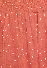 Tissu rouge à pois blancs, doté d'une taille froncée et d'une texture plissée. Textile doux, léger et au tombé fluide.
