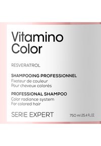 Profesjonell sjampoflaske for farget hår. Hvit og rosa design, med fet svart tekst som sier "Vitamina Color" og ingredienser. 750 ml.