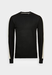 Svart stickad tröja med rundad halsringning, med krämfärgade ränder längs axlarna och ärmarna. Ribbad mudd och nederkant. Slät textur.