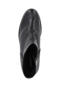 Bottine en cuir noir avec une texture lisse, bout rond et fermeture éclair sur le côté. L'intérieur présente le logo de la marque sur un doublure douce.