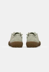 Zapatos verde claro con una parte superior texturizada, suela de goma con protuberancias y un diseño sencillo de cordones.
