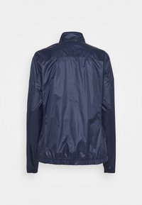 Marinblå lättviktsjacka med hög krage, elastisk nederkant och en slät yta. Har subtila sömdetaljer vid axlarna.