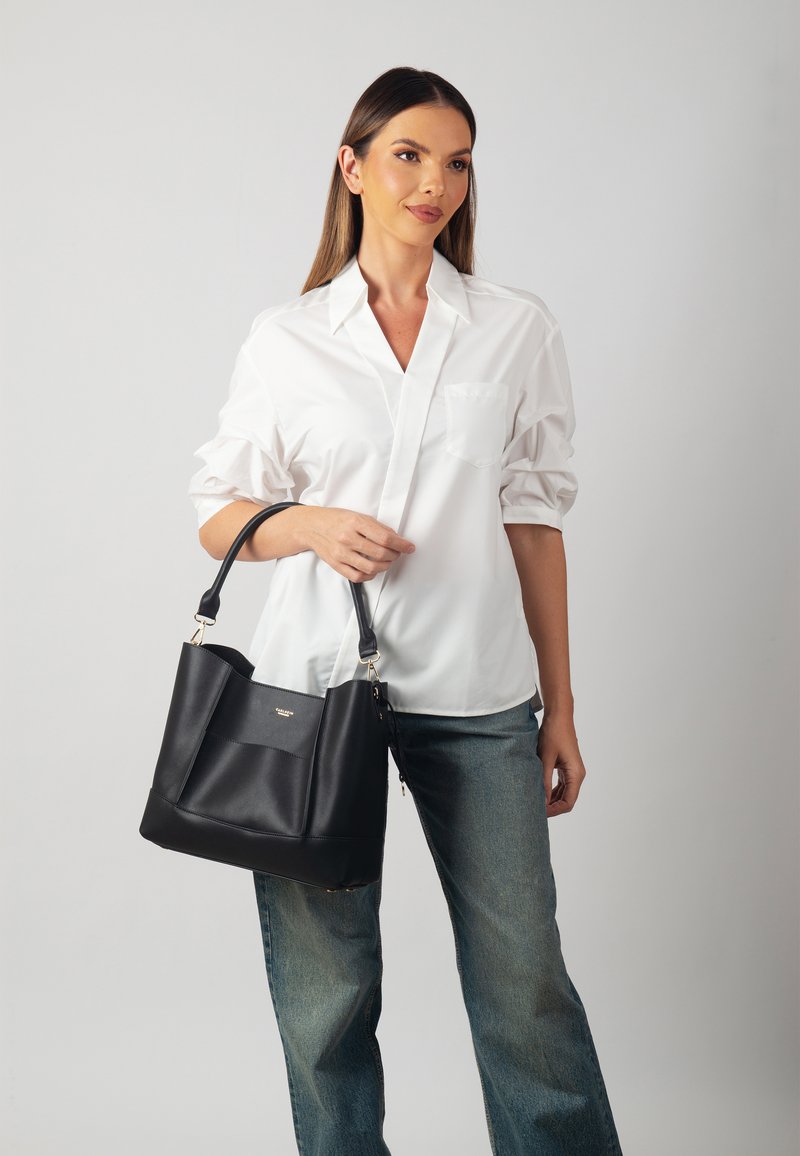 Borsa a tote nera in pelle con forma strutturata, caratterizzata da una texture liscia e dettagli in hardware dorato. Design minimalista con cuciture decorative.